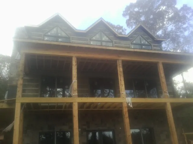 Dormers and porch framing on a large log home under construction — Roof Coating work by our crew in Eureka
